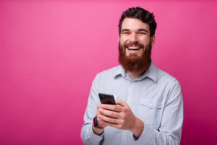 Smiling man with smartphone on his hand looking at dating apps