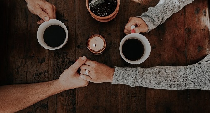 couple holding hands while drinking coffee together