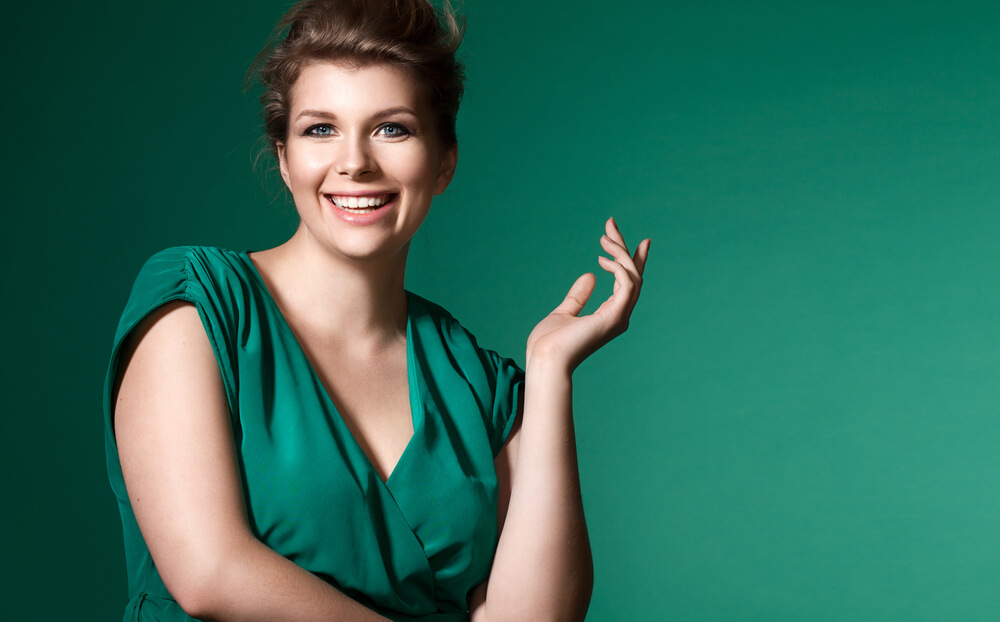 Confident curvy woman dressed in green, smiling