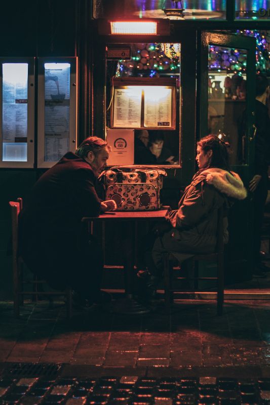 a man and a woman sitting in front of a restaurant having a serious conversation